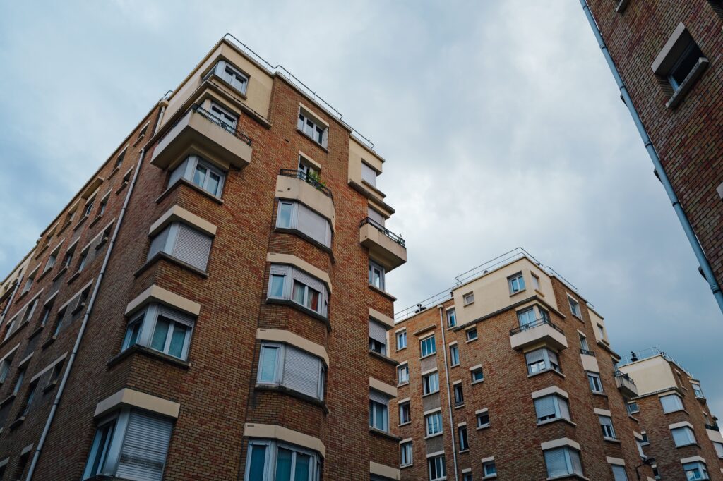 Urban brick apartment buildings under a cloudy sky, showcasing city living architecture.